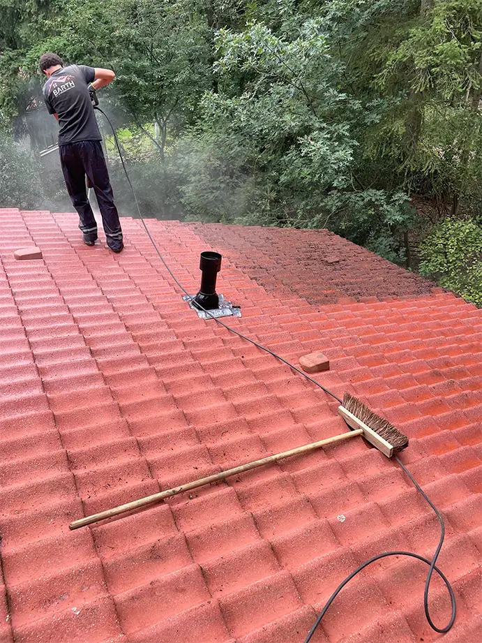 Onderhoud aan een dak waarbij vuil en mos van de dakbedekking wordt verwijderd
